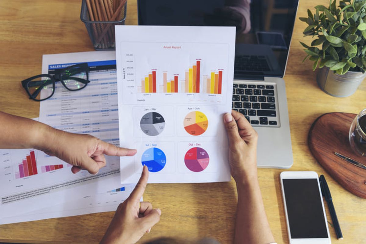 Profesional analizando reportes empresariales y gráficos financieros en laptop para apoyar decisiones de marketing basadas en datos Hiweb
