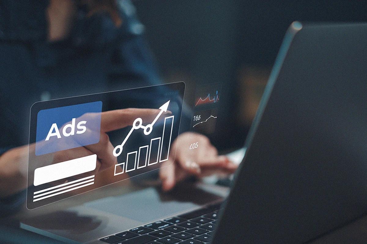 A person managing Google Ads on a laptop, viewing a dashboard with charts