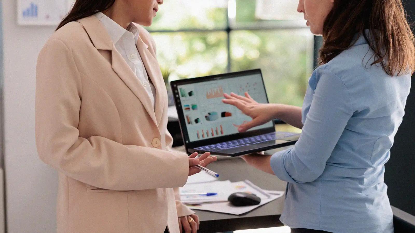 Two women reviewing a customer data chart on a CRM platform