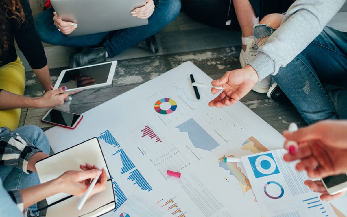 Miembros de un equipo industrial analizando proyectos empresariales, reportes, gráficos y estrategias de marketing digital en conjunto Hiweb