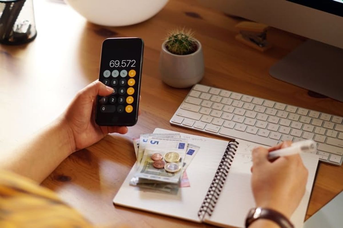 Entrepreneur managing personal finances with a calculator, notes and computer tools, representing digital business planning and performance analysis Hiweb