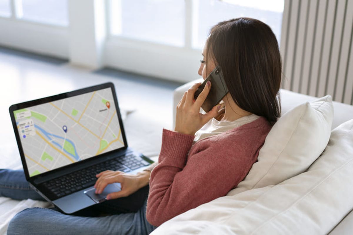 Persona buscando ubicaciones inmobiliarias en línea utilizando una laptop y teléfono mientras explora opciones de propiedades Hiweb