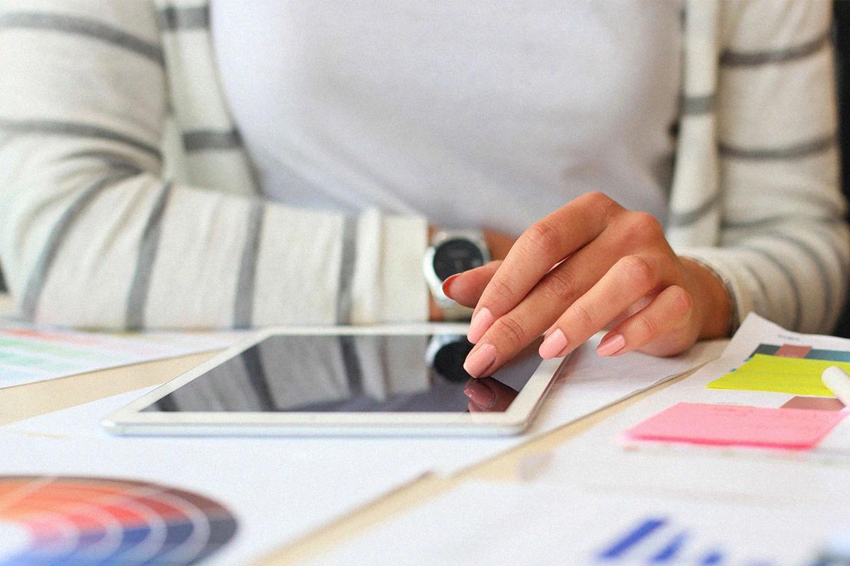 Persona usando un ipad sobre materiales gráficos como paletas de colores y post its