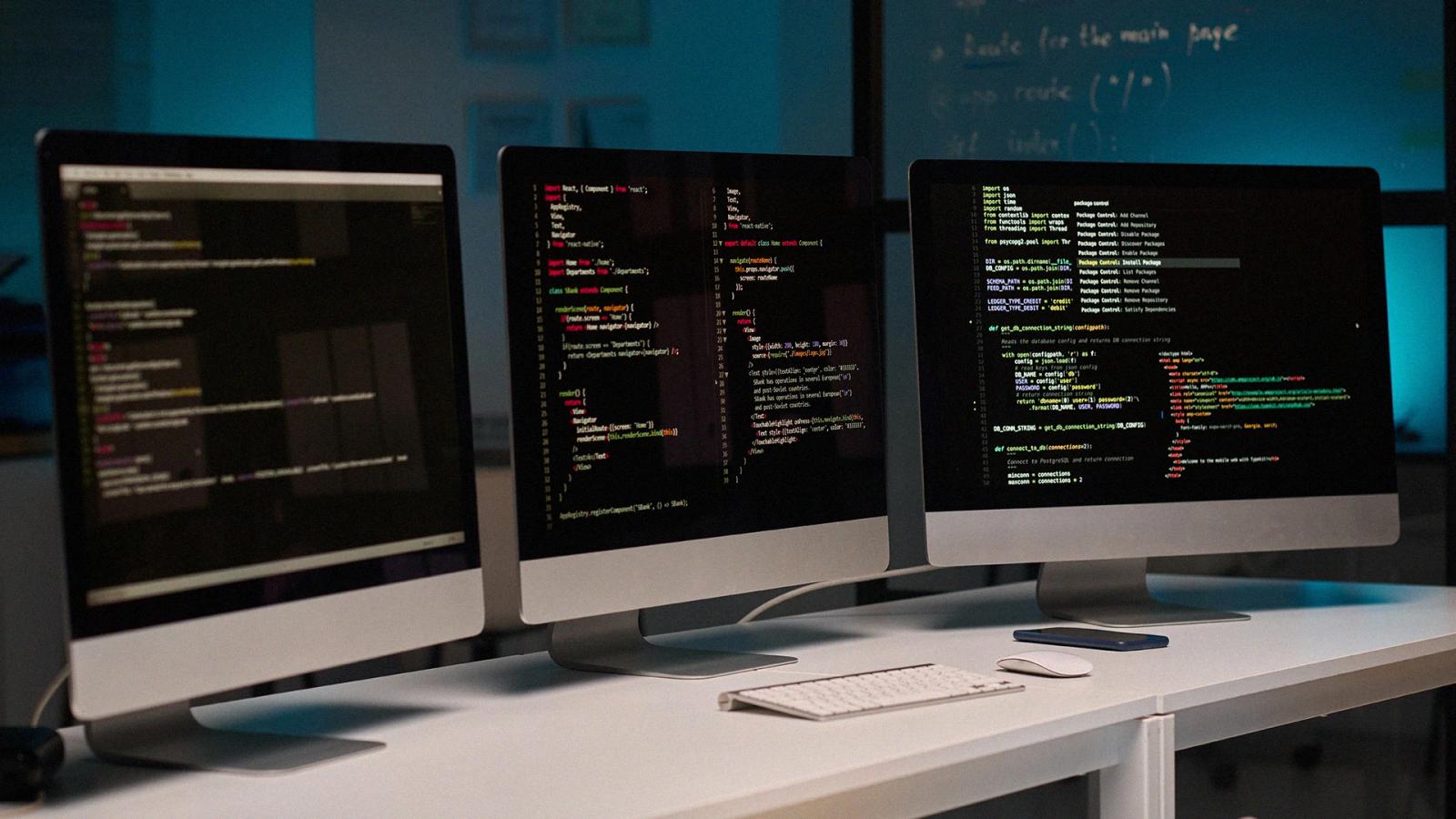 Pantallas de computadoras con código de programación representando desarrollo de software, tecnología digital y soluciones SaaS para empresas Hiweb.