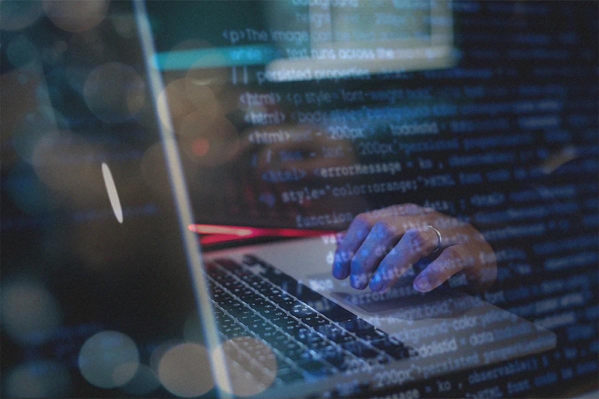 Hands typing on a keyboard with web code overlaid