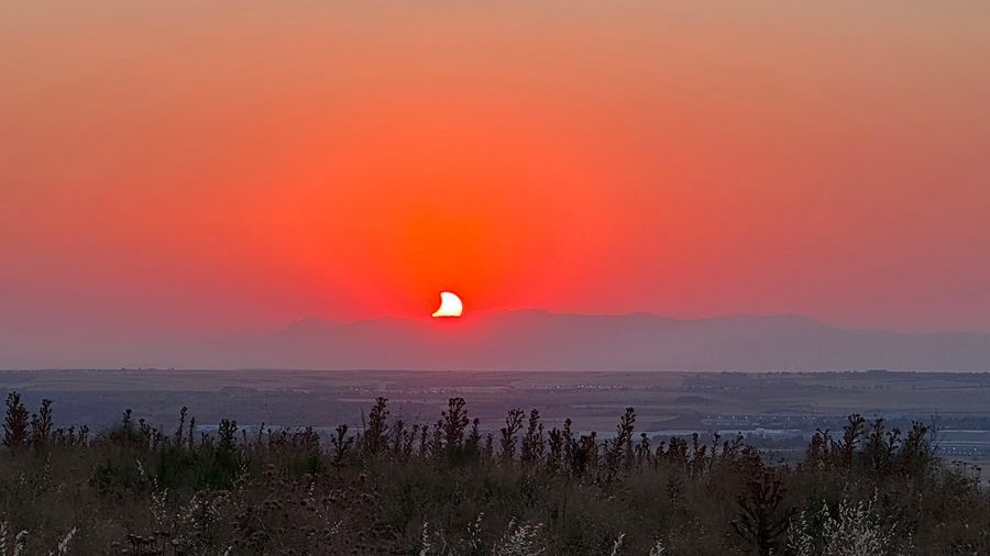 Eclipse parcial sobre el horizonte, al atardecer