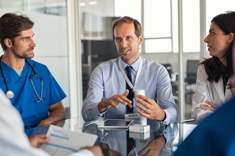 Compliance officer discussing best practices with medical staff in a boardroom.