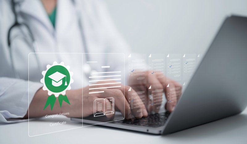 Person in a doctor's uniform typing on a laptop as illustrations of certifications pass along their fingers as they type.