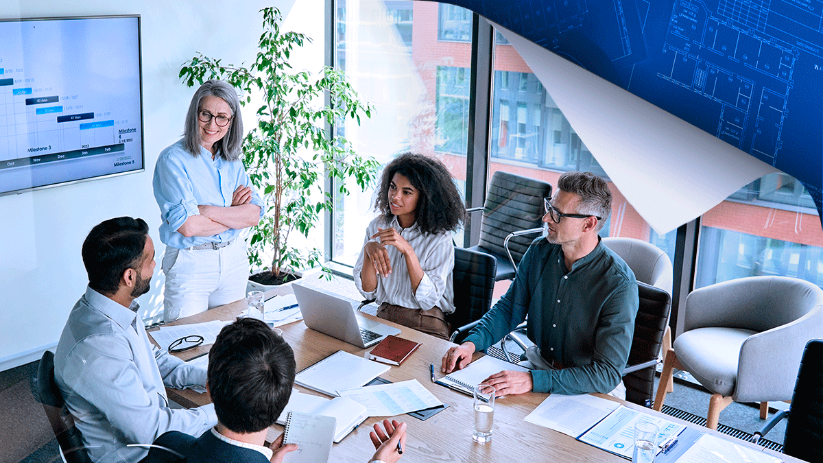 Five professionals in a modern office meeting around a conference table, with city views and data charts displayed on wall monitors.