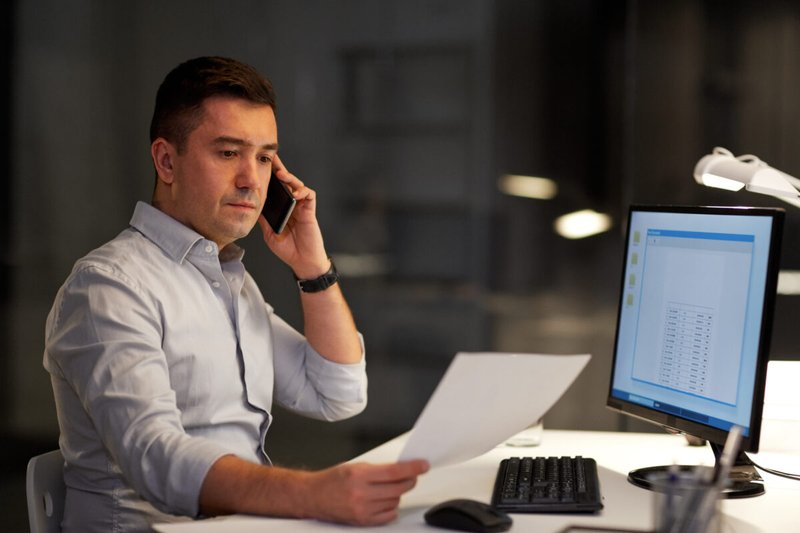 L&D professional working late on the phone while putting together a revised training plan for a major hospital.