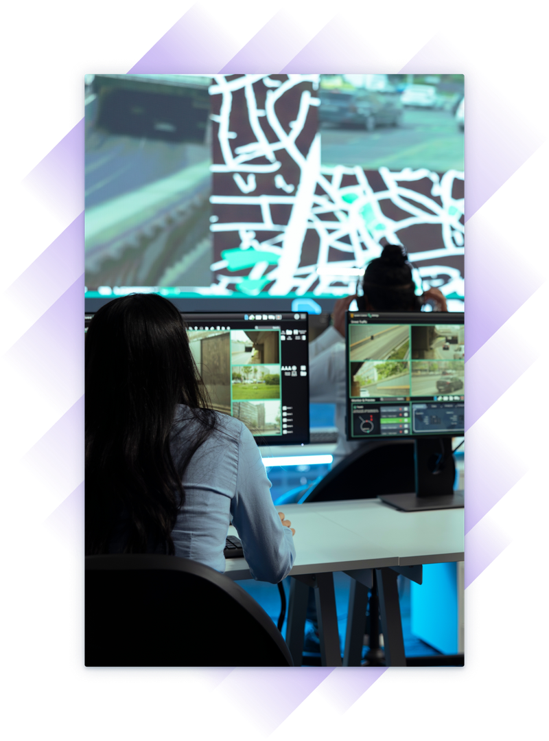 Woman in background stands in front of a large screen that has maps with associated images while a woman watches at a row of computer in an instructor-led training session.