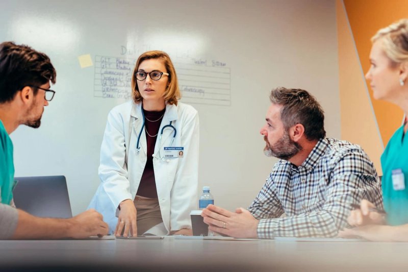 Doctor speaking in a conference room with other medical and training professionals sharing her opinion.