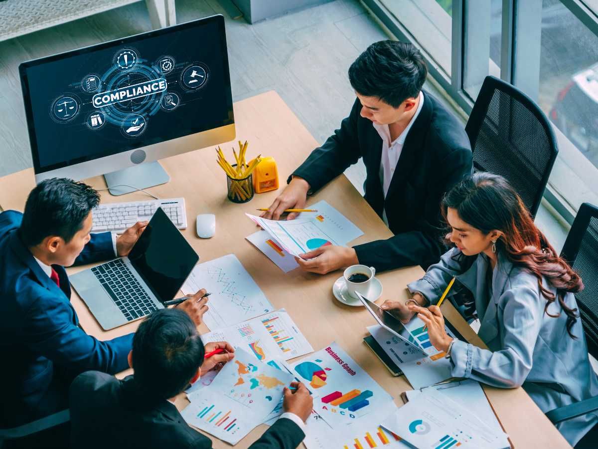 Training professionals at a desk working together to solve compliance issues.