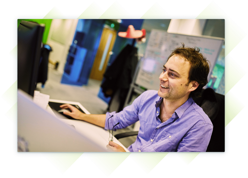 A team member smiling as he works at his computer.