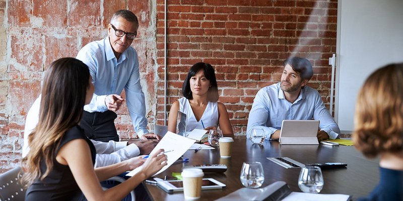 Businesspeople in a meeting in modern boardroom through a glass pane.