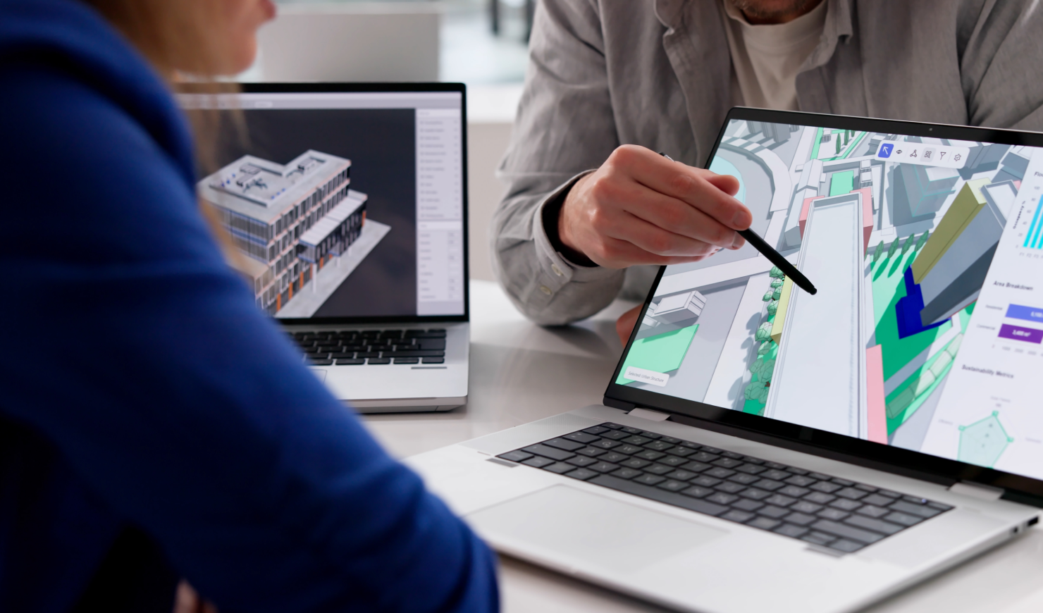 Man gesturing at a 3-D map on a laptop with his pen while explaining something to the learner seated in front of him.