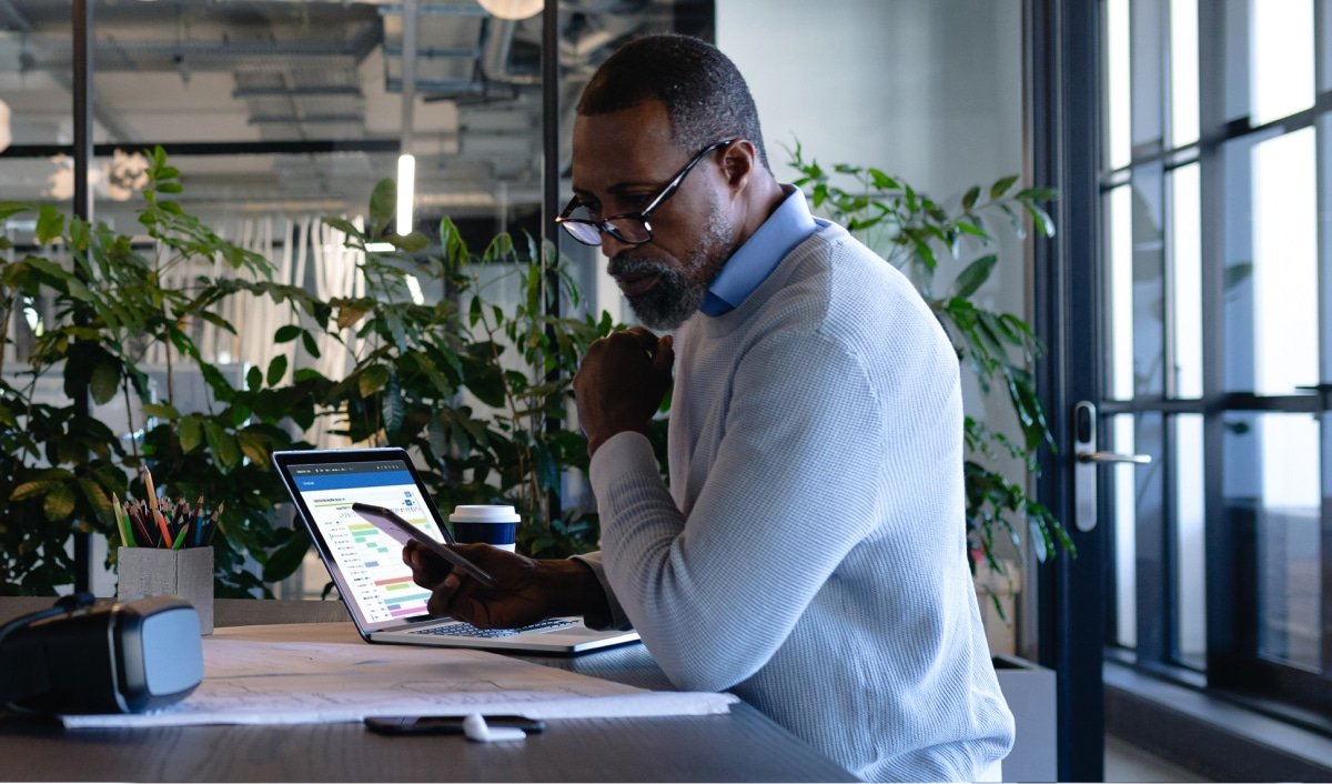 Training professional looks at his phone while Administrate solves complex training schedules automatically on his laptop in the background.
