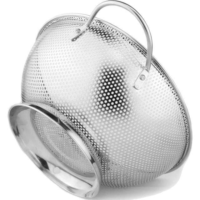 Perforated stainless steel colander with two wire loop handles and a raised ring base, tipped on its side