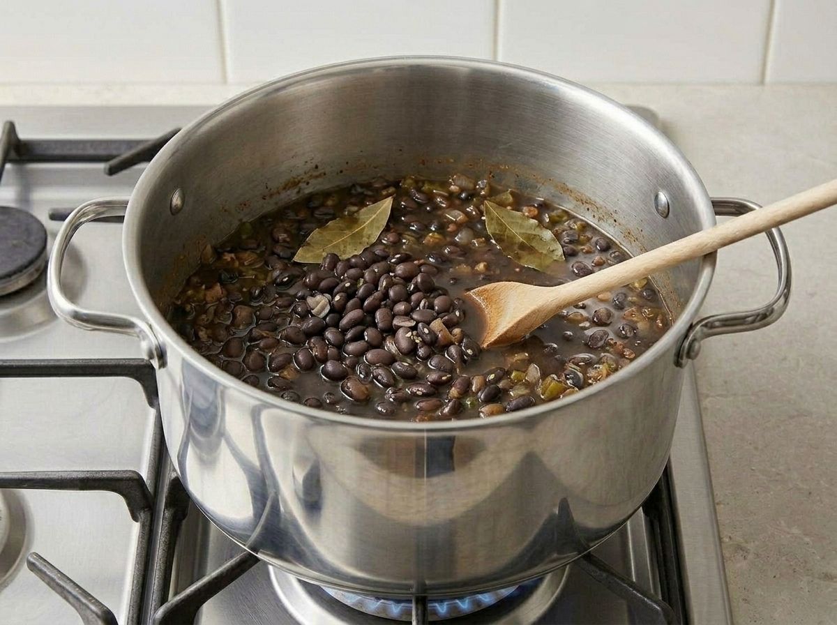 Undrained black beans, vegetable broth and two bay leaves tipped into the pot with the sofrito