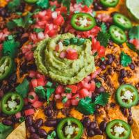 Vegan nachos topped with spicy cashew cheese, black beans, and jalapeños.