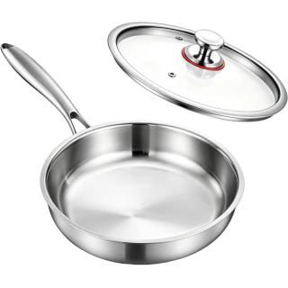 Polished stainless steel skillet with a long handle and a glass lid resting behind it