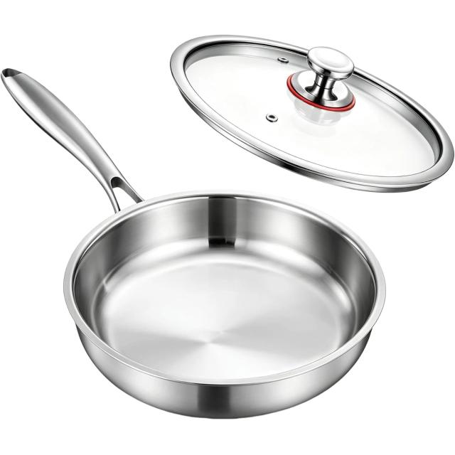 Polished stainless steel skillet with a long handle and a glass lid resting behind it