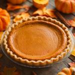 Slice of vegan pumpkin pie with a flaky crust on a white plate.