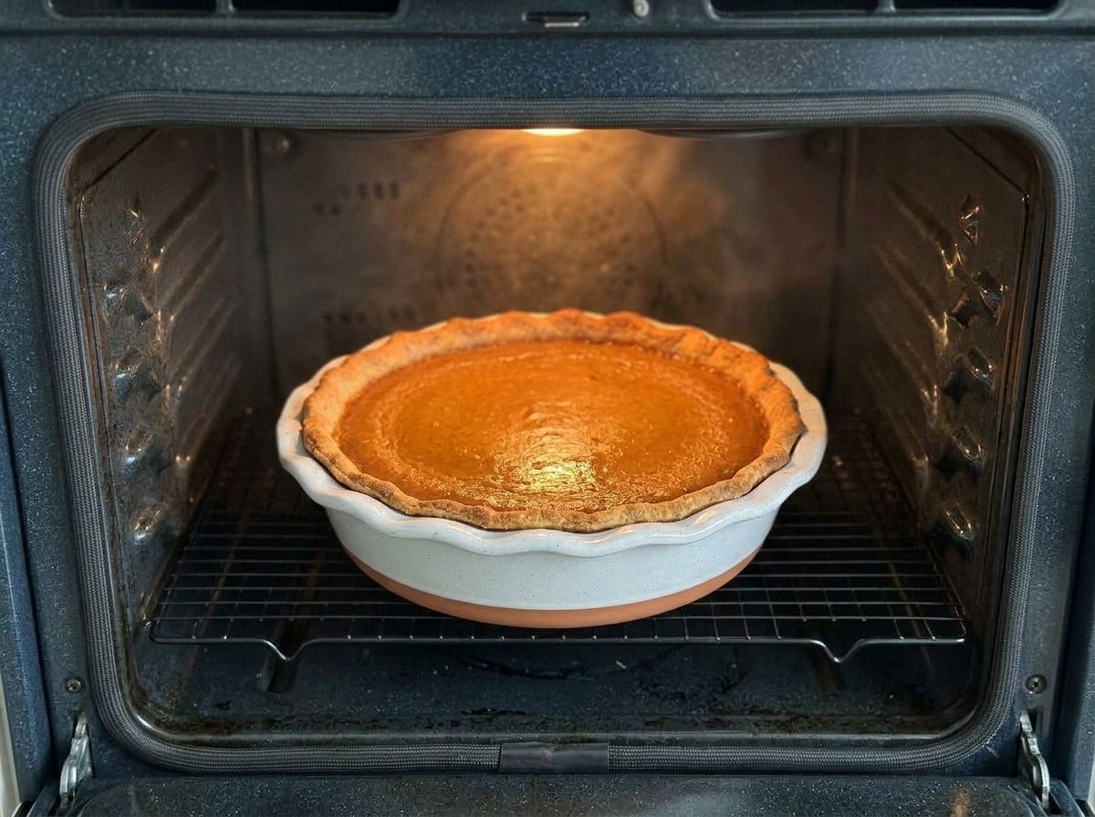 The pie baking in the oven, the pastry edge golden and the center still faintly glossy