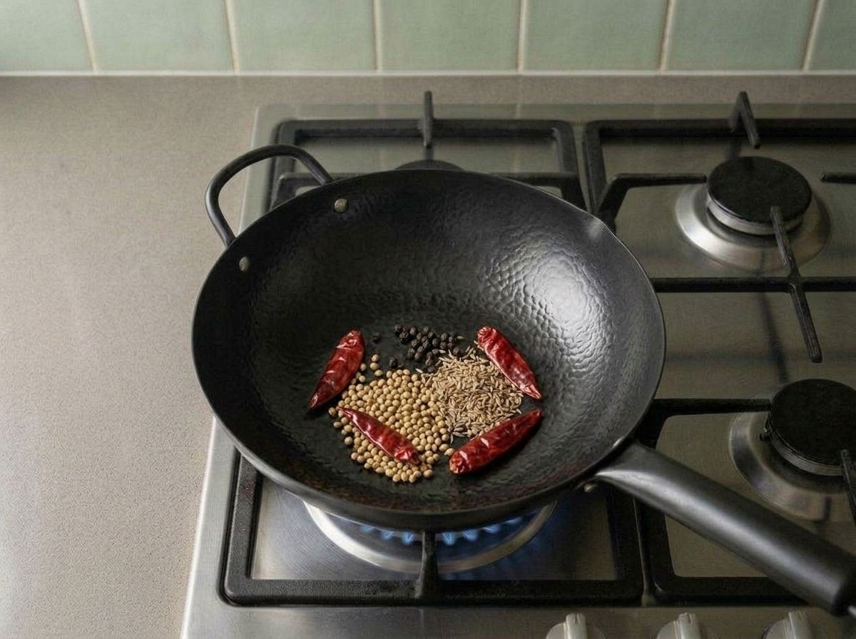 Coriander seeds, cumin, peppercorns and dried red chilies toasting in a dry wok
