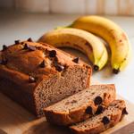 Vegan banana bread loaf surrounded by ripe bananas and walnuts on a wooden table.