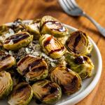 Crispy roasted Brussels sprouts drizzled with balsamic glaze on a white plate.