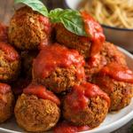 Plate of vegan meatballs garnished with herbs, served on a wooden table.