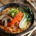Bowl of vegan ramen with mushrooms, carrots, and fresh greens in broth.