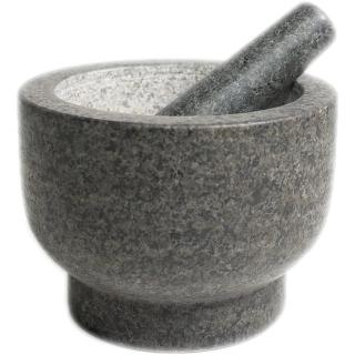 A deep gray granite mortar with a pale unpolished interior and a footed base, with its granite pestle resting inside.