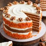 Slice of vegan carrot cake with creamy vegan frosting and walnuts on top.