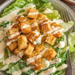 A fresh Vegan Caesar Salad with romaine lettuce, croutons, and creamy dressing on a wooden table.