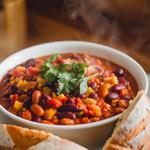 Bowl of hearty vegan chili with beans and lentils, garnished with cilantro.