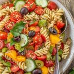 Vibrant vegan pasta salad with cherry tomatoes, cucumber, and bell pepper.