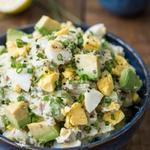 Avocado egg salad in a deep blue bowl, chunks of green avocado and pieces of hard-boiled egg folded through a creamy pale green base with chives and cracked black pepper.