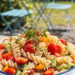 A vibrant pasta and vegetable salad with cherry tomatoes, cucumbers, bell peppers, and a light dressing.