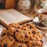 Stack of vegan oatmeal cookies on a white plate with scattered oats.