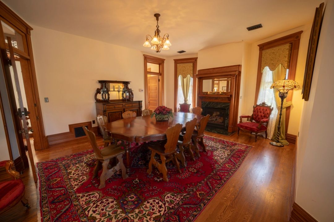 The Buffalo Bill Suite, with a dining table, fireplace and Persian rug
