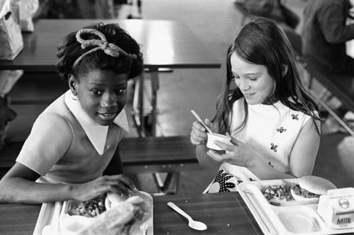 Photograph of two young girls eating lunch in a school cafeteria