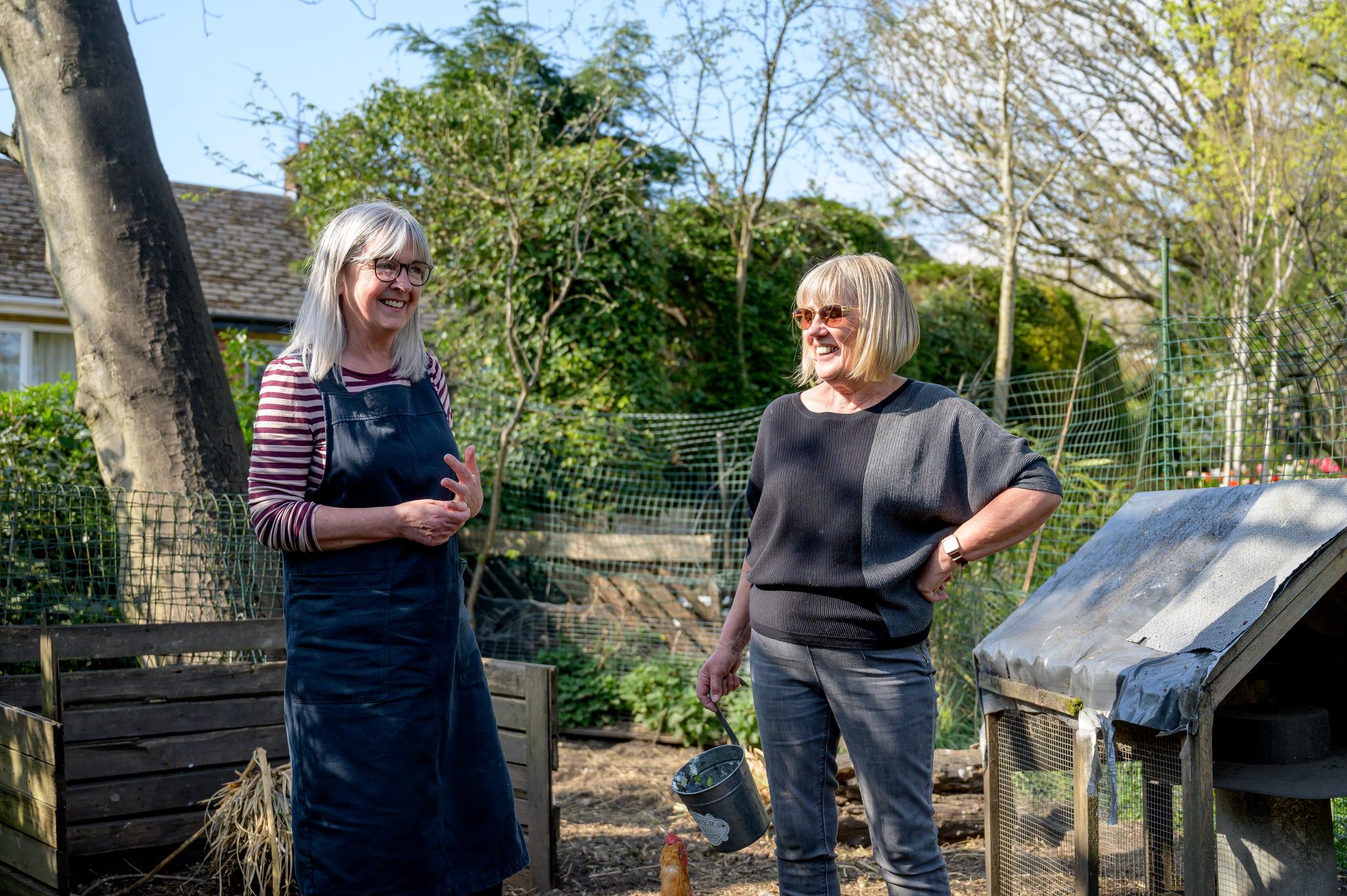 Two women in a garden, laughing.