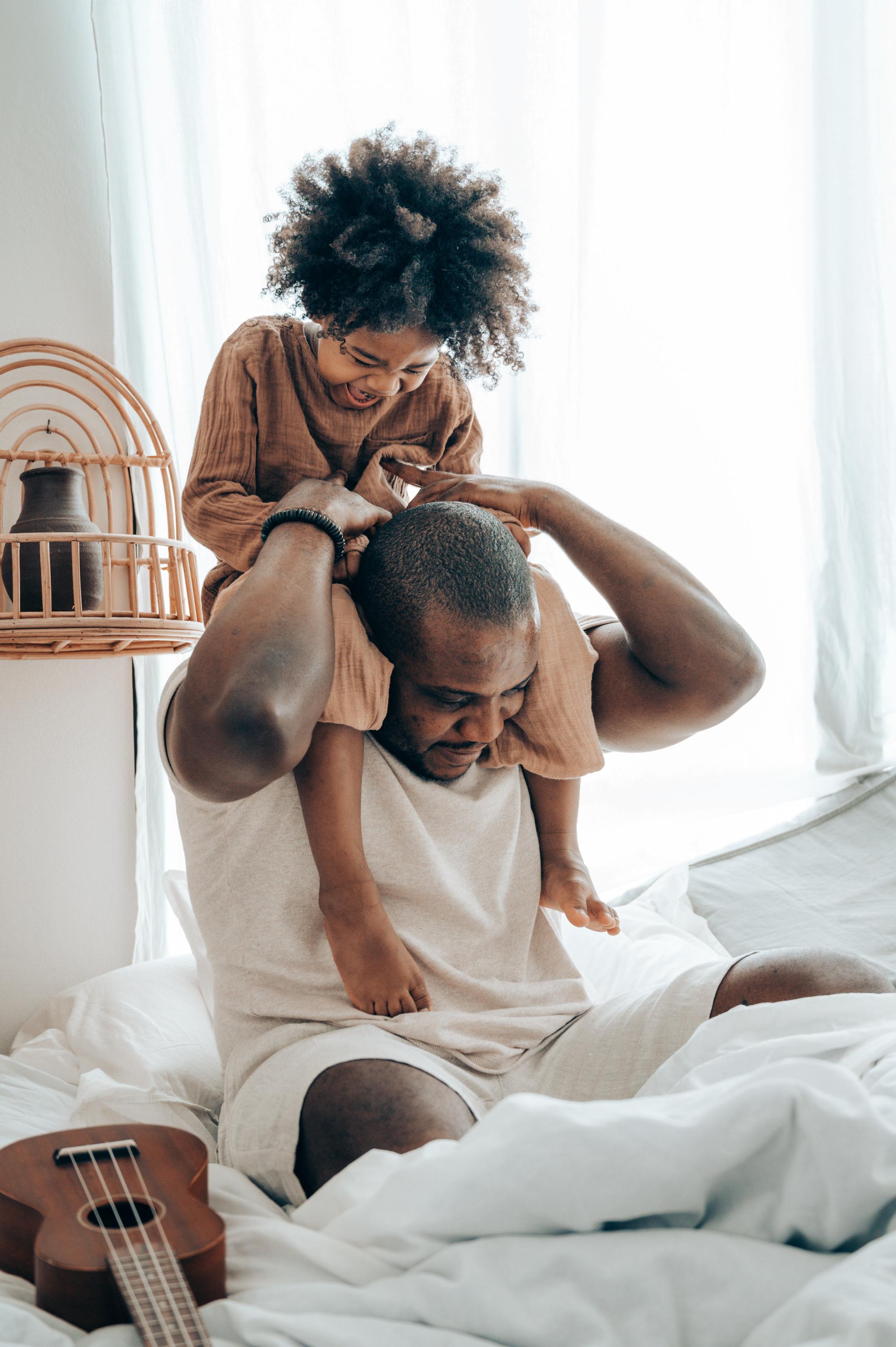 A man playing with his granddaughter  in bed