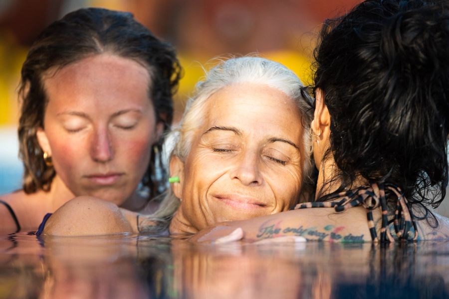 Mujeres de un retiro abrazadas dentro del agua