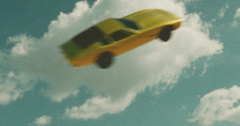 Yellow car flying in a blue sky with clouds.