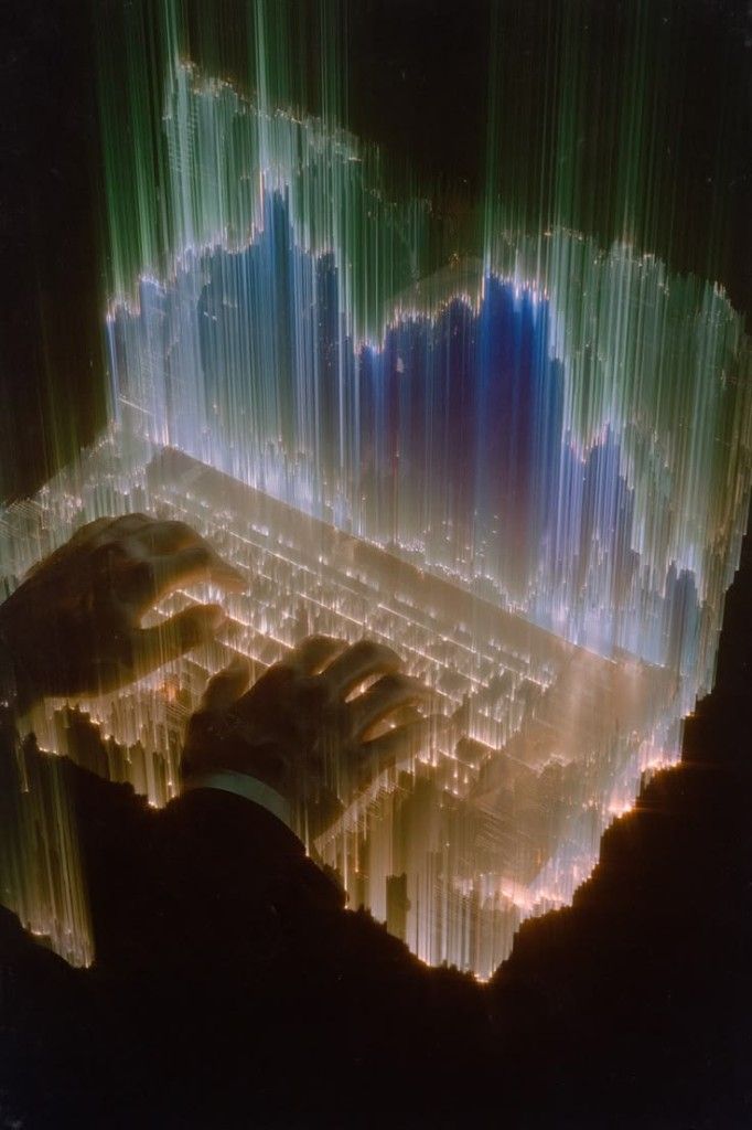 Hands typing on a glowing keyboard beneath green and blue vertical light trails.