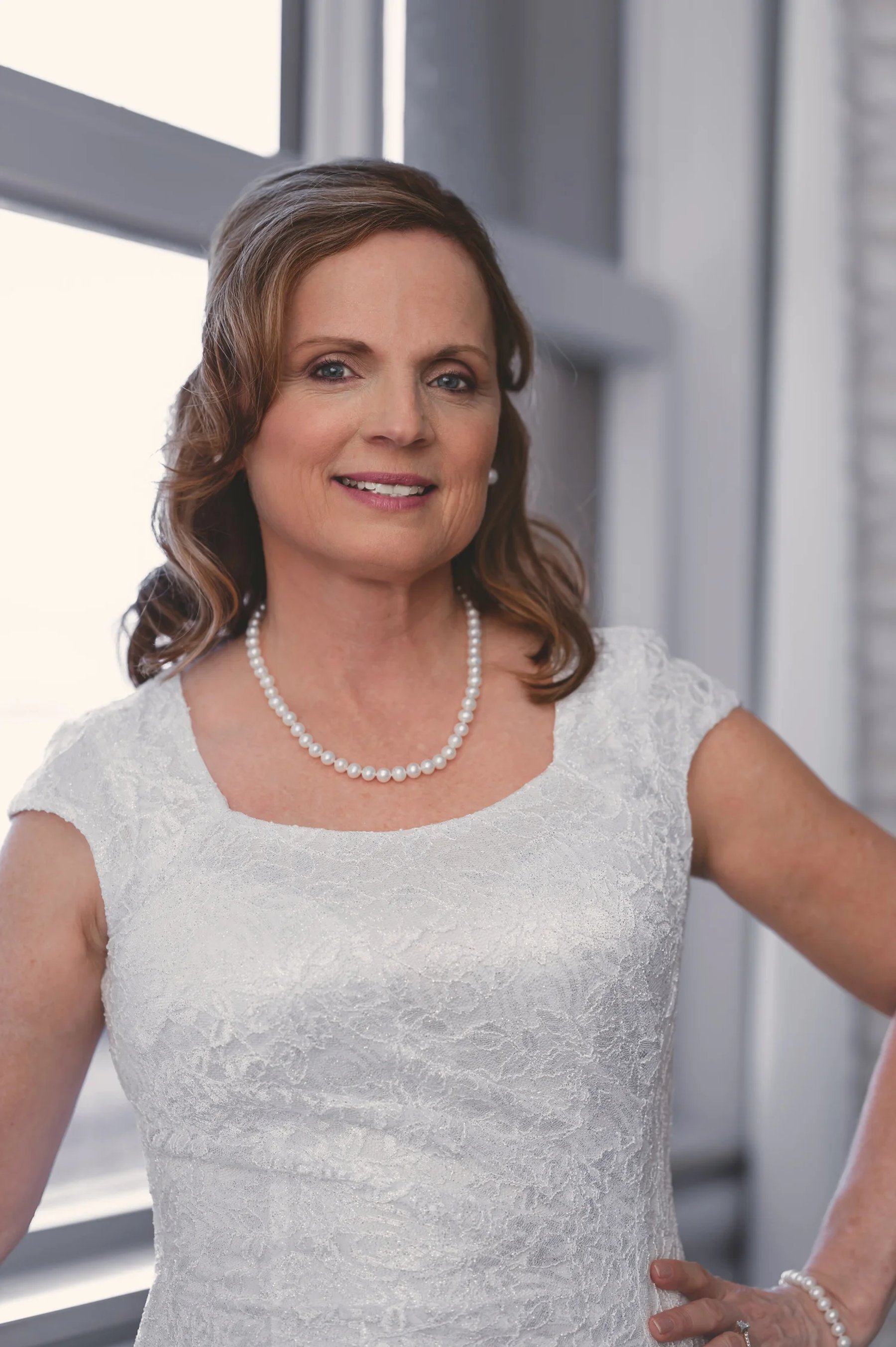 An individual portrait of a woman standing beside a porch in natural light