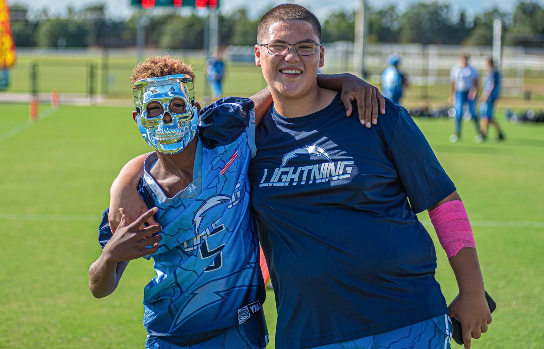 Two people in blue Lightning football apparel standing together on a sports field